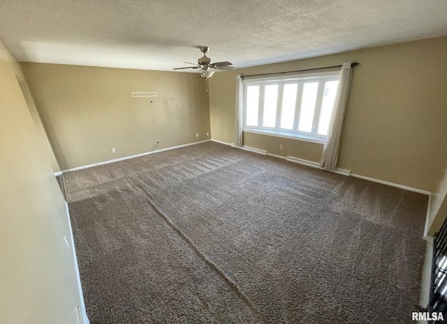 spare room featuring dark colored carpet, ceiling fan, and a textured ceiling