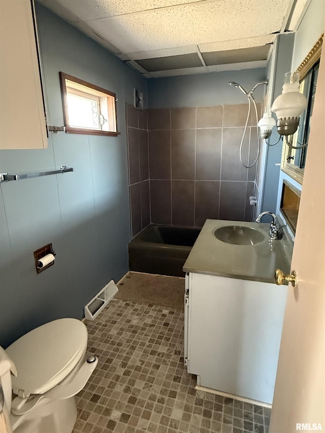 bathroom with walk in shower, vanity, toilet, and a drop ceiling