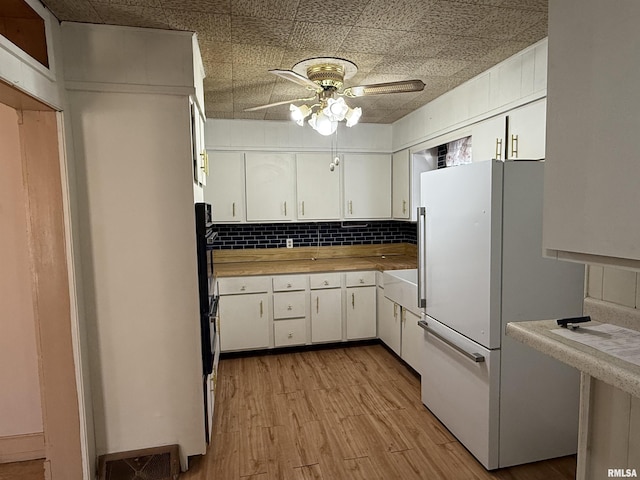 kitchen with high end fridge, white cabinets, and backsplash