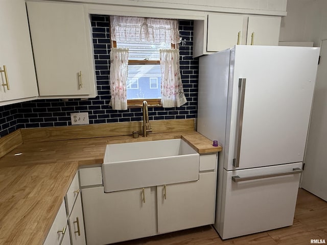 kitchen featuring sink, backsplash, white cabinets, and white fridge