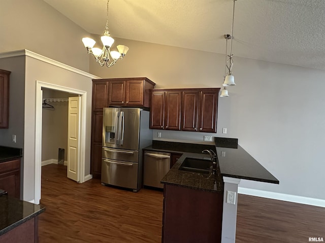 kitchen with stainless steel appliances, decorative light fixtures, kitchen peninsula, and sink