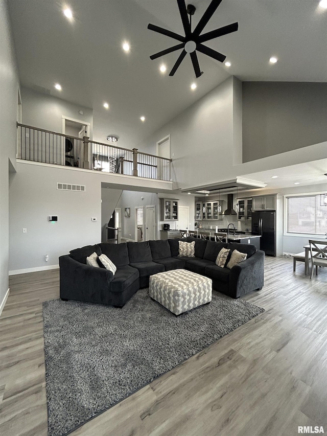 living room with hardwood / wood-style flooring, high vaulted ceiling, and ceiling fan