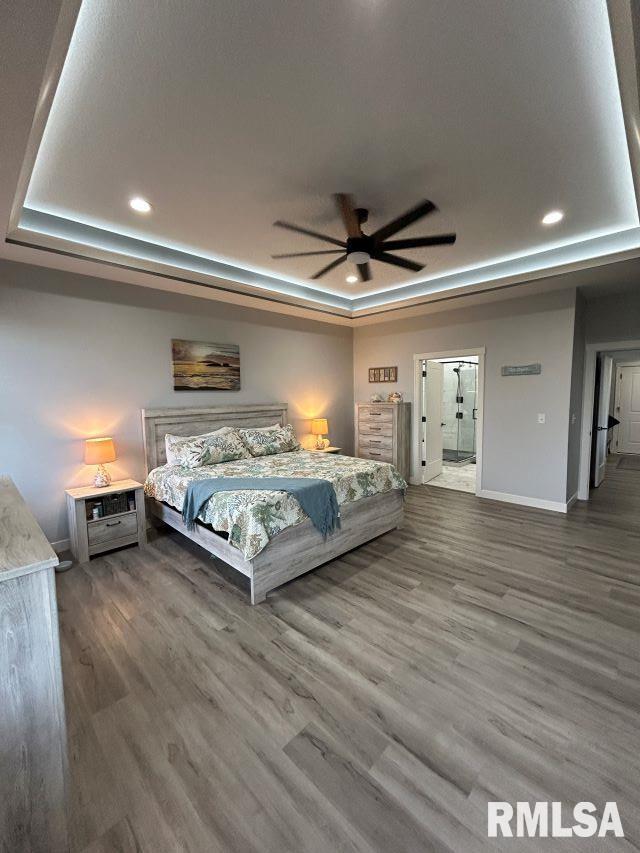 unfurnished bedroom with a raised ceiling, ceiling fan, and dark hardwood / wood-style flooring