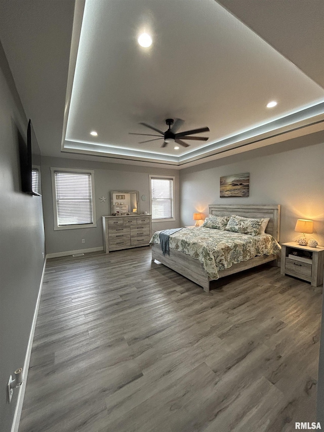 unfurnished bedroom featuring hardwood / wood-style flooring, ceiling fan, and a tray ceiling