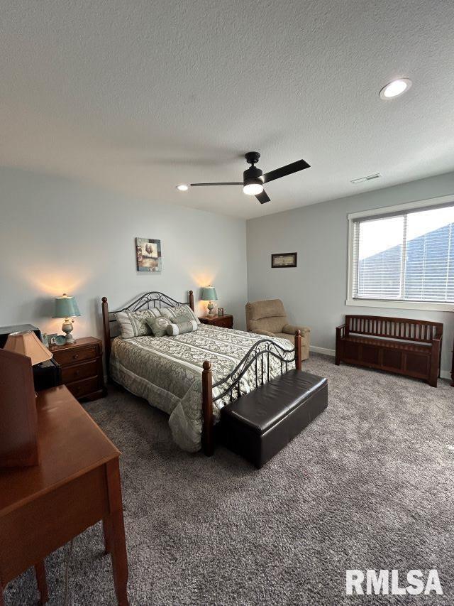 bedroom with ceiling fan, a textured ceiling, and dark colored carpet