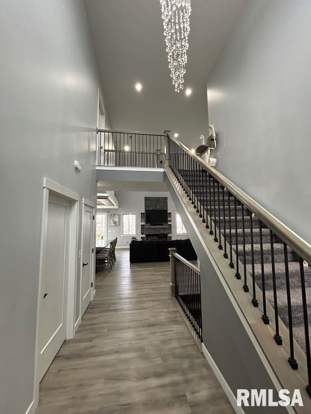 staircase with a towering ceiling, hardwood / wood-style floors, and a notable chandelier