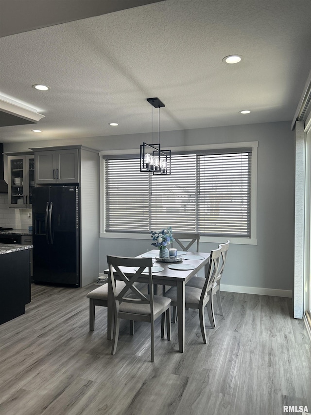 dining area featuring an inviting chandelier, wood-type flooring, and a textured ceiling