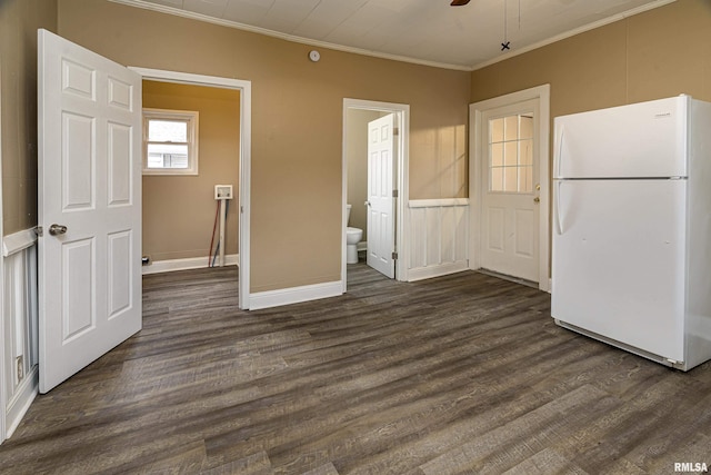 unfurnished bedroom with crown molding, dark wood-type flooring, ensuite bath, and white refrigerator