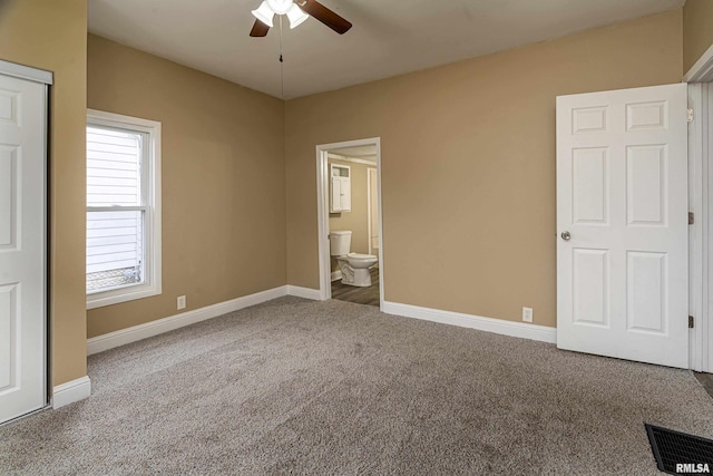 unfurnished bedroom with ensuite bath, carpet floors, and ceiling fan