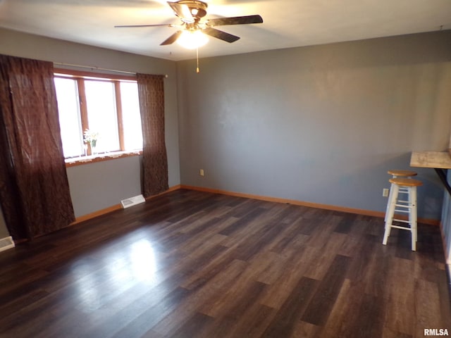 unfurnished room featuring dark wood-type flooring and ceiling fan