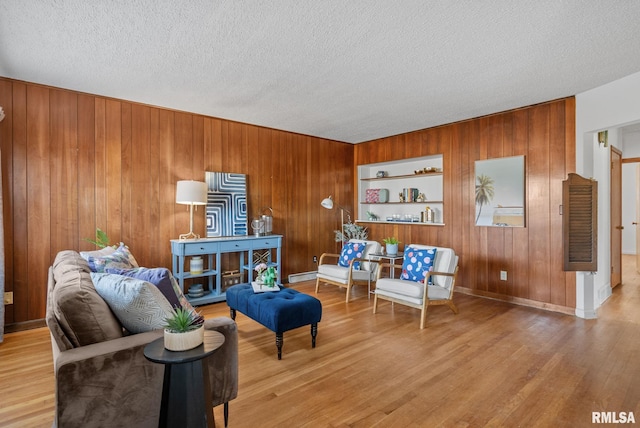 sitting room with wood-type flooring, built in features, wooden walls, and a textured ceiling