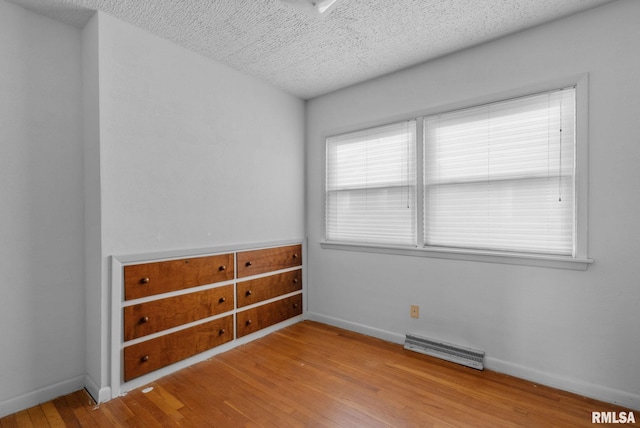 spare room featuring a textured ceiling and light hardwood / wood-style floors