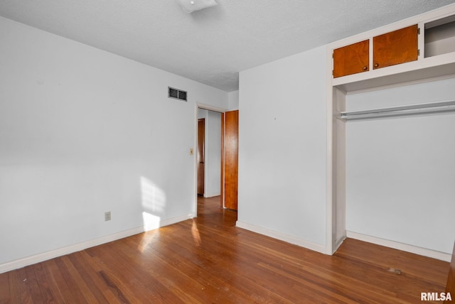 unfurnished bedroom with wood-type flooring, a closet, and a textured ceiling