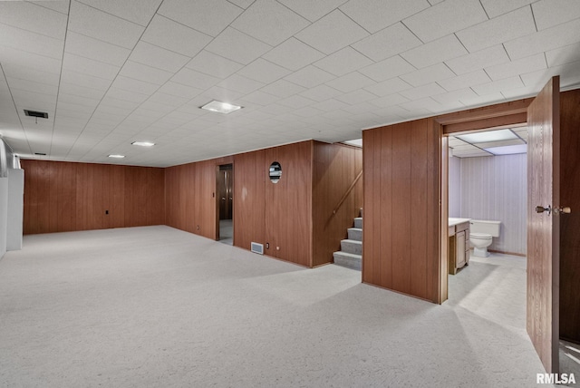 basement with wooden walls and light colored carpet