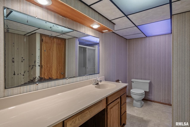 bathroom with walk in shower, a paneled ceiling, vanity, and toilet