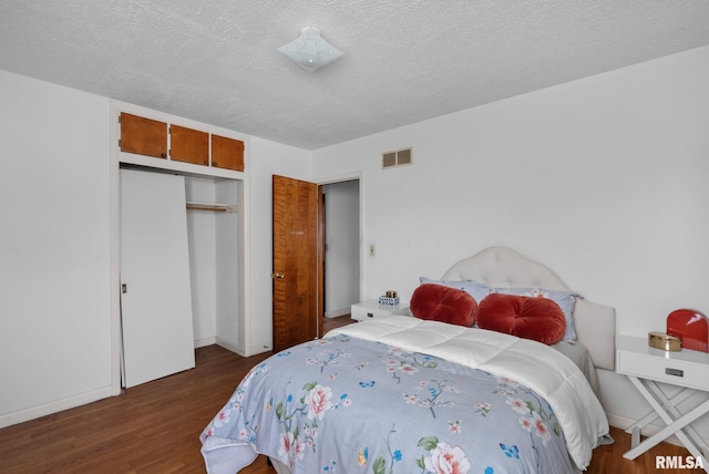 bedroom featuring dark wood-type flooring, a closet, and a textured ceiling