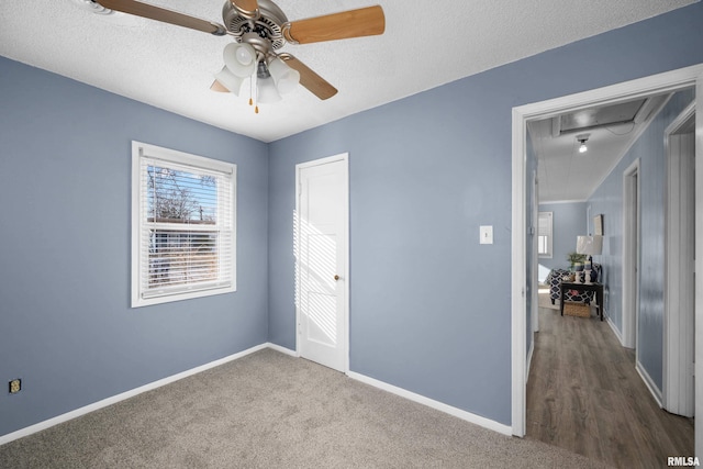 unfurnished bedroom with dark colored carpet, ceiling fan, and a textured ceiling