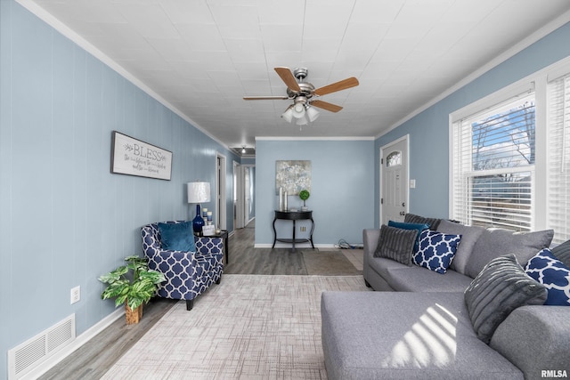 living room featuring wood-type flooring, ornamental molding, and ceiling fan