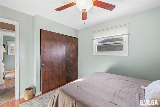 bedroom featuring ceiling fan, a closet, and light wood-type flooring