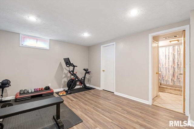 exercise area featuring light hardwood / wood-style flooring and a textured ceiling