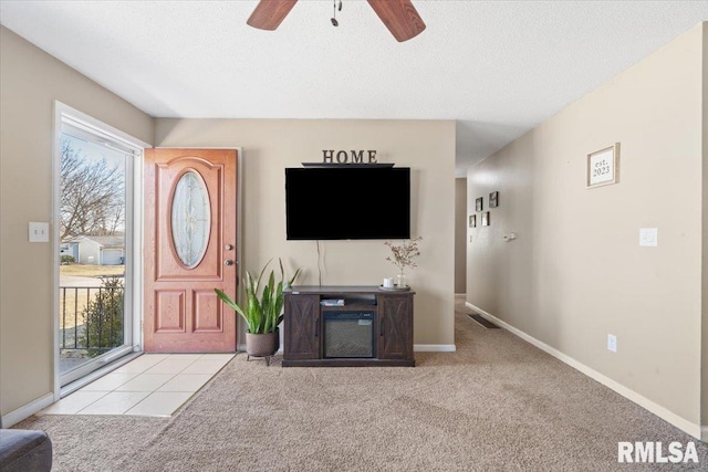 unfurnished living room with ceiling fan, light colored carpet, and a textured ceiling