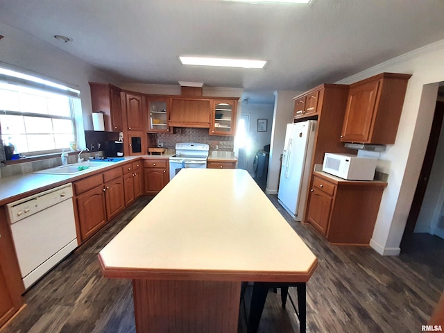 kitchen with dark hardwood / wood-style floors, sink, decorative backsplash, a center island, and white appliances