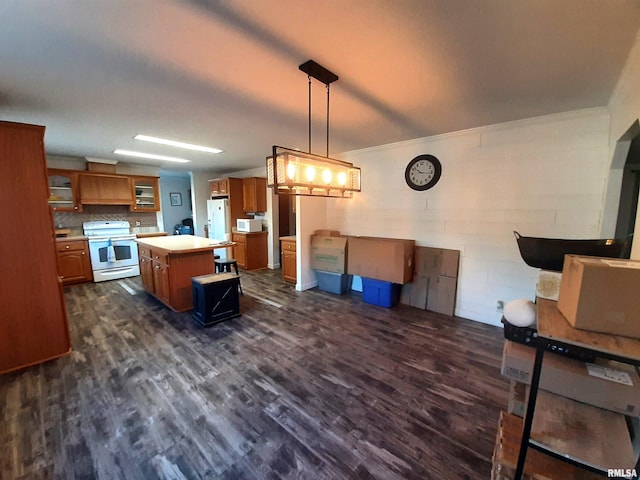 kitchen featuring white appliances, decorative light fixtures, dark hardwood / wood-style floors, and a kitchen island