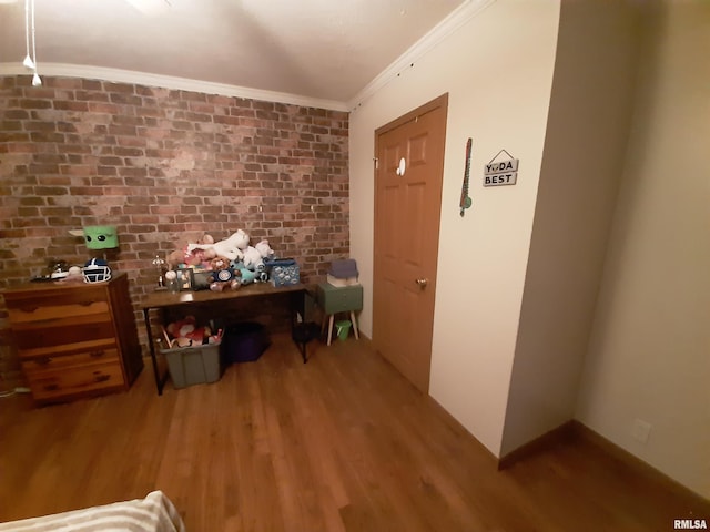 home office featuring hardwood / wood-style flooring, ornamental molding, and brick wall