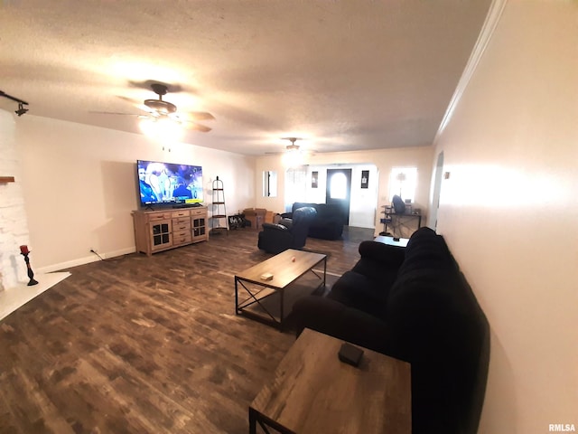 living room with a textured ceiling, ornamental molding, dark hardwood / wood-style flooring, ceiling fan, and a fireplace