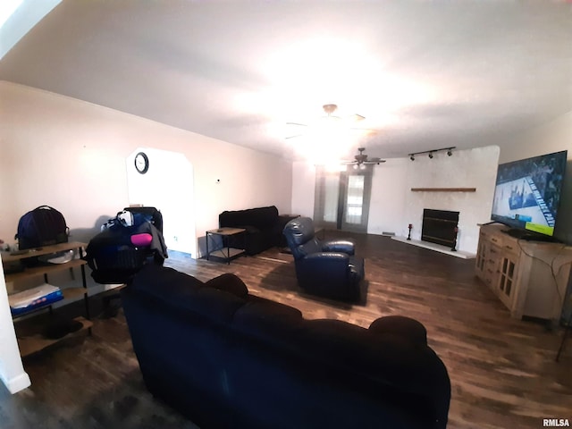 living room featuring ceiling fan, rail lighting, a fireplace, and dark hardwood / wood-style flooring