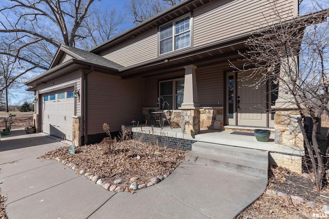 view of front of home with stone siding, a porch, concrete driveway, and an attached garage