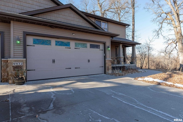 view of front of property with a porch, concrete driveway, an attached garage, and stone siding