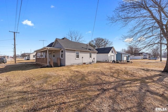 rear view of house featuring a lawn and a porch