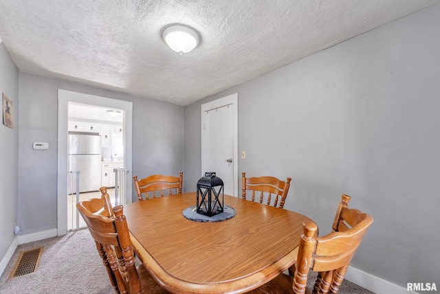 dining room with carpet floors and a textured ceiling