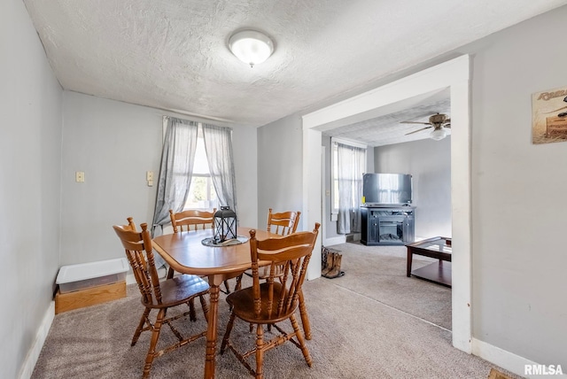 dining space with a textured ceiling, carpet floors, and a healthy amount of sunlight