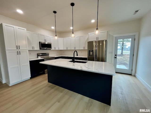 kitchen featuring a sink, stainless steel appliances, light stone counters, and light wood-style floors