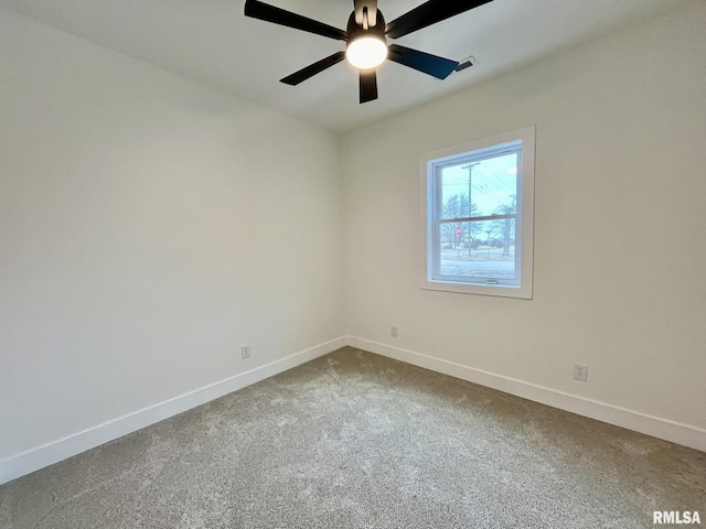 empty room with dark colored carpet, baseboards, and a ceiling fan