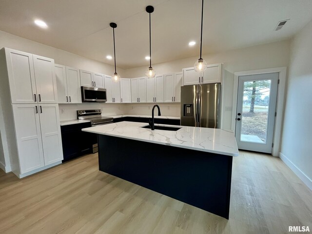 kitchen featuring white cabinetry, sink, stainless steel appliances, and a center island with sink