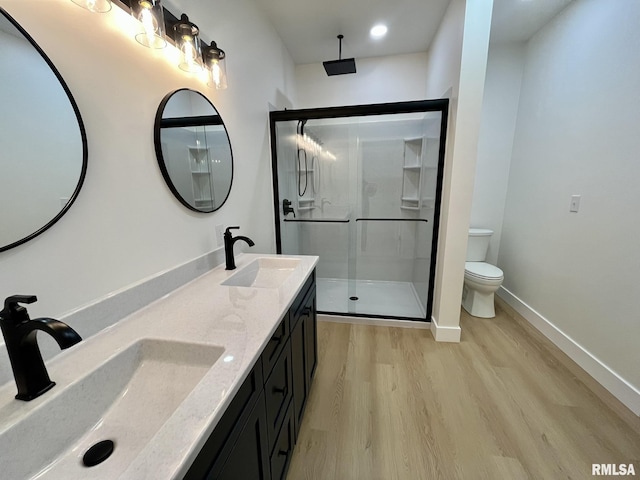 bathroom featuring a sink, toilet, a stall shower, and wood finished floors