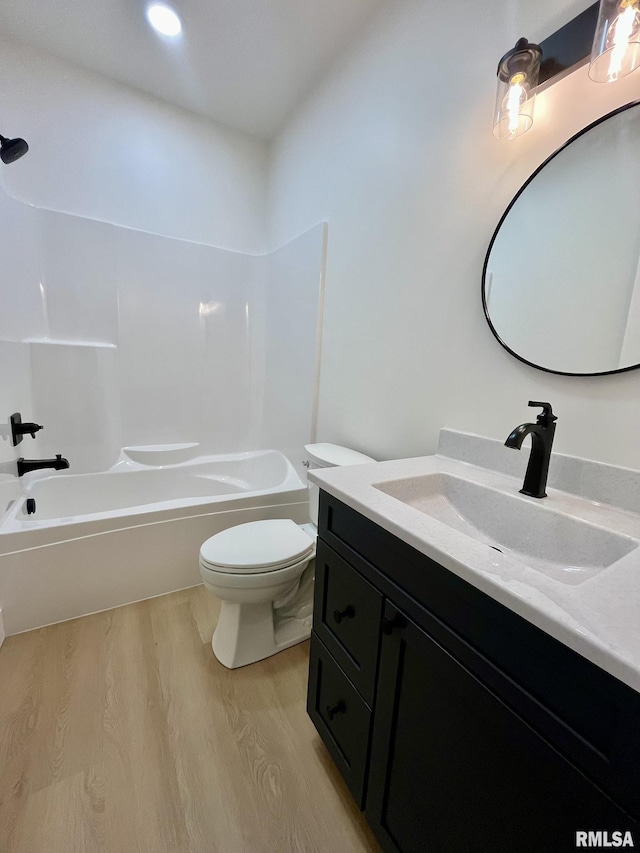 bathroom featuring toilet, vanity, bathtub / shower combination, and wood finished floors