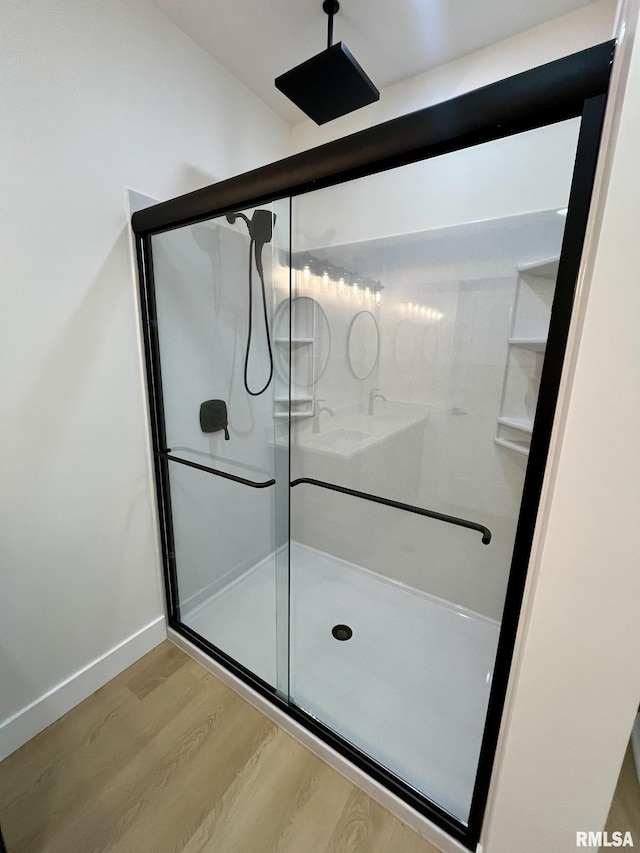 full bathroom featuring wood finished floors, a stall shower, and baseboards