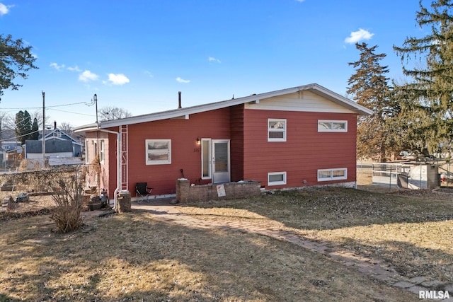 rear view of house featuring a lawn and fence