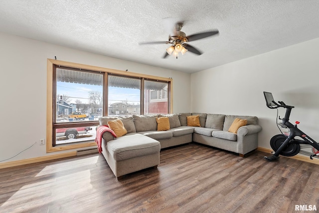 living area with a ceiling fan, a textured ceiling, baseboards, and wood finished floors