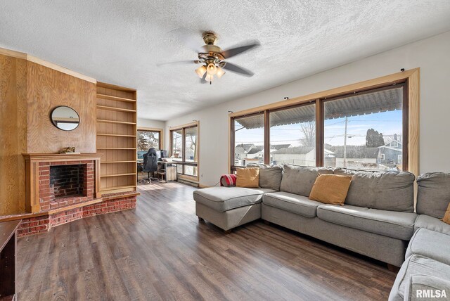 living room featuring dark wood finished floors, a fireplace, a textured ceiling, and ceiling fan