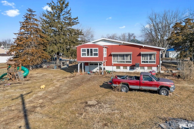 view of front of property featuring a garage, a playground, and a front yard