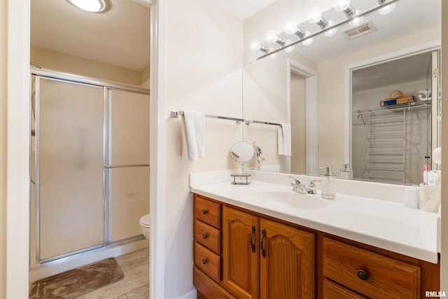 bathroom featuring vanity, toilet, and a shower with shower door