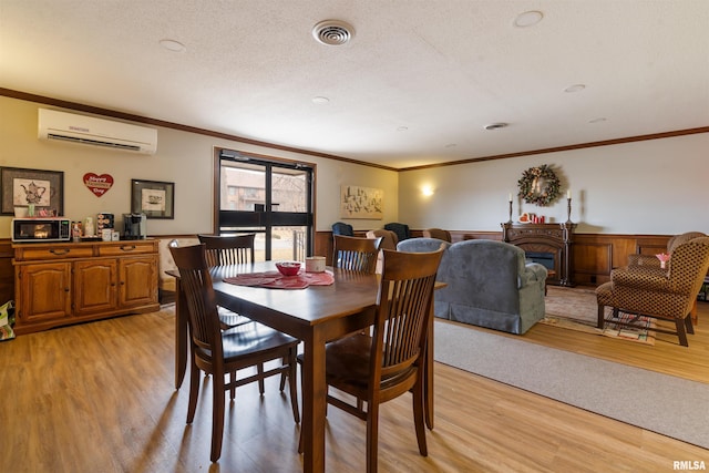 dining space with crown molding, a wall mounted air conditioner, a textured ceiling, and light hardwood / wood-style flooring