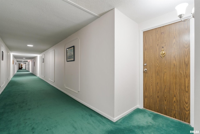 hallway featuring dark carpet and a textured ceiling