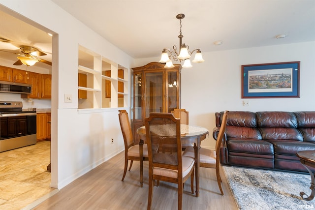 dining room with ceiling fan with notable chandelier and light hardwood / wood-style flooring