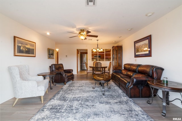 living room with wood-type flooring and ceiling fan with notable chandelier